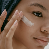 A woman applying anti-aging cream with visible key ingredients like retinoids and hyaluronic acid.