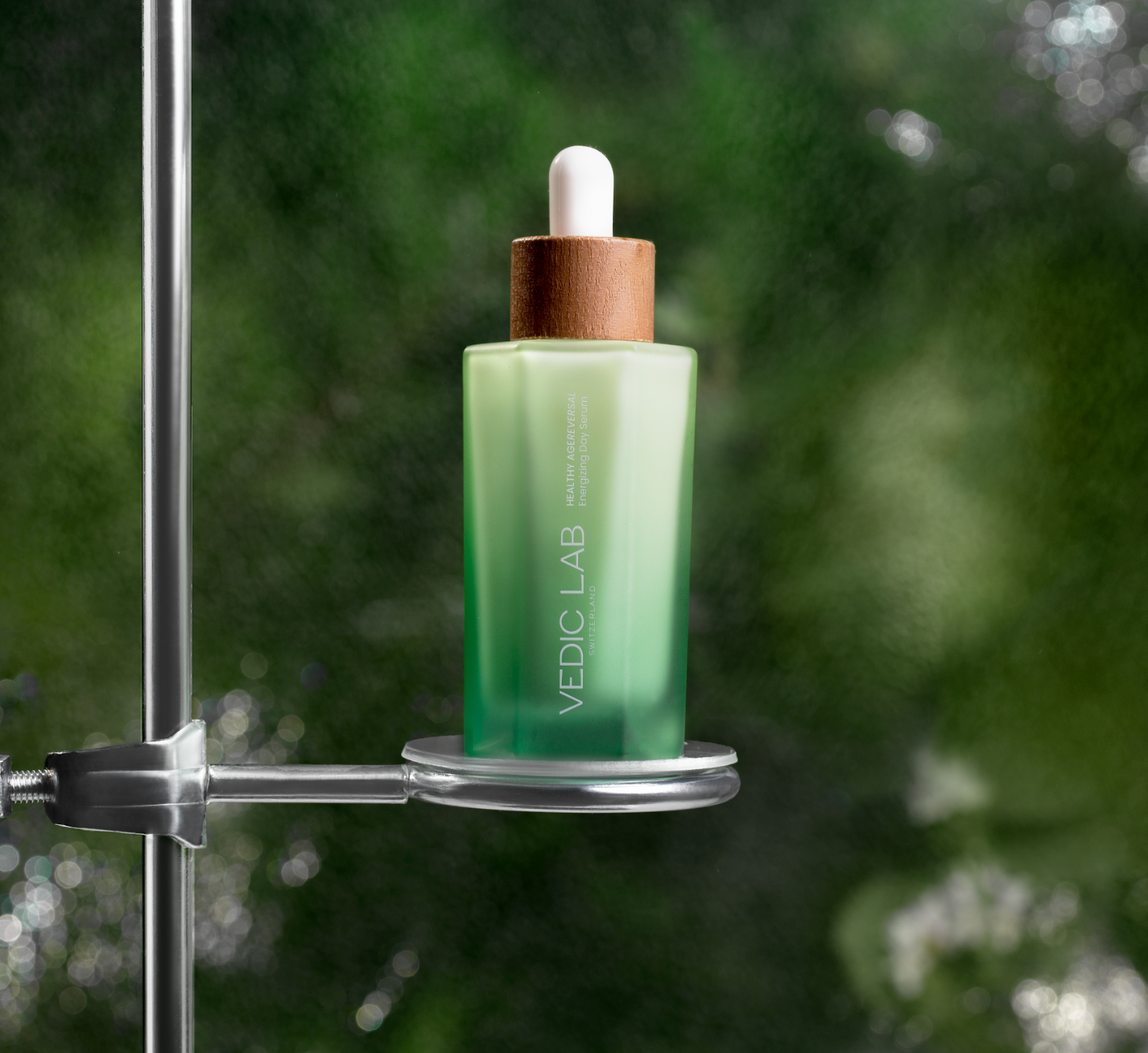 Vedic Lab green gradient bottle with dropper on metal stand. Blurred nature background. Sleep recovery serum.